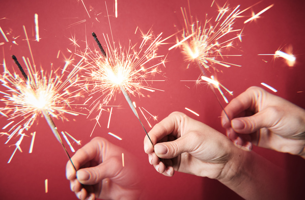Duplicate image of a sparkler flaring brightly in the hand on a fuchsia background