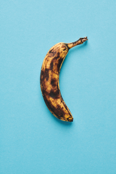 The peel of a ripe banana in dark spots lying on a blue surface