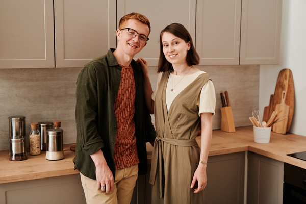 A couple of young people smiling and hugging each other in a bright kitchen