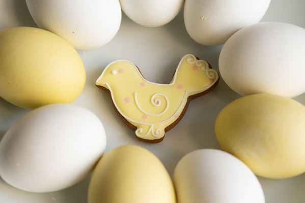 Yellow and white Easter eggs are laid around a glazed gingerbread in the form of a chicken