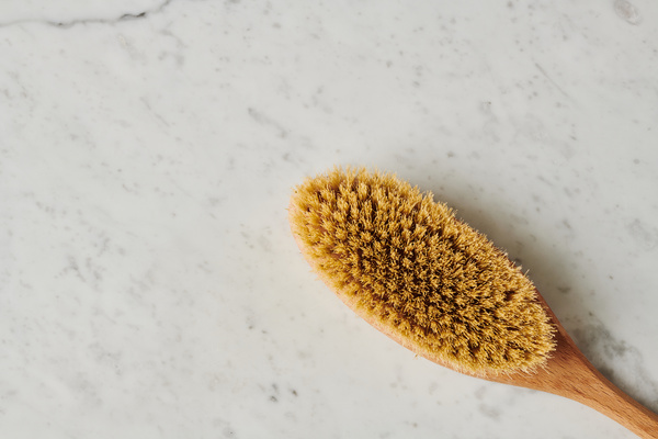 Top view of a natural dry massage brush lying on a marble surface