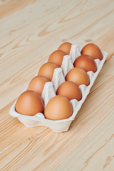 A package with a dozen brown eggs standing on a wooden surface