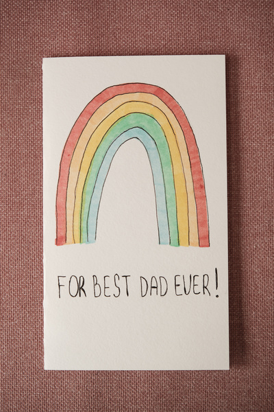 Handmade postcard for Fathers Day with a bright rainbow pattern and congratulations on a pink background