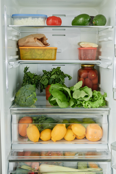 Shelf and drawer of the refrigerator with fresh greenery and healthy citrus fruits