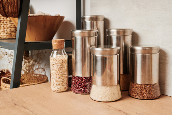Reusable containers for bulk foods made of metal and glass standing on a wooden kitchen table