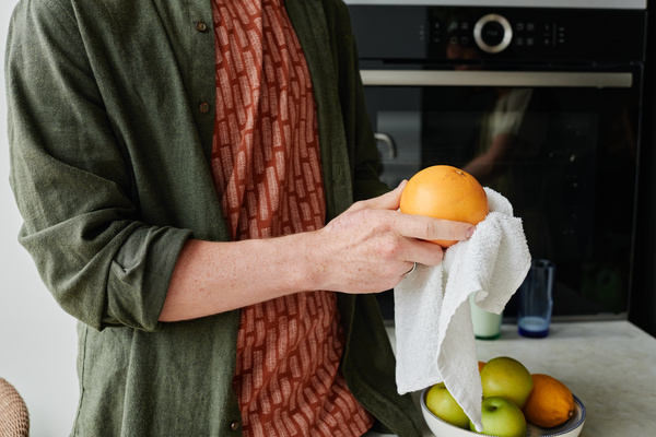 Grapefruit is wiped with a white towel by a man in a green shirt over a red T-shirt