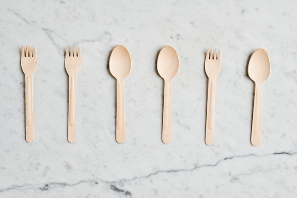 Disposable eco-friendly cutlery laid out in a row on a marble surface