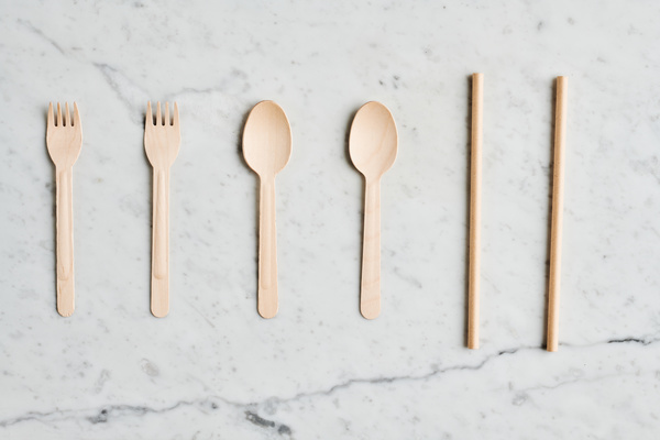 Disposable organic cutlery and drink straws laid out in a row on a marble surface