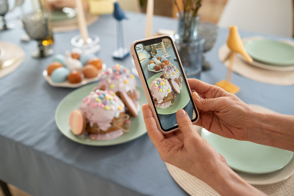 Photographing Easter cakes in pink glaze on a festive table with a blue tablecloth setting on Easter with a phone
