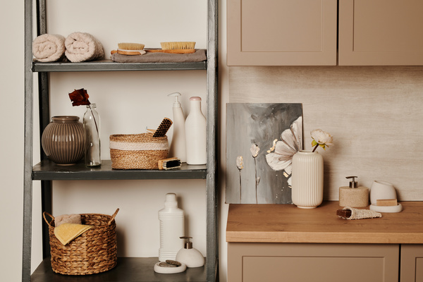 Eco-friendly toiletries are placed on gray shelves and a wooden cabinet with braided baskets and vases