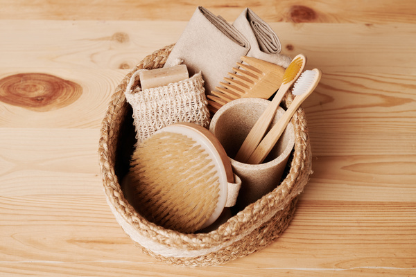 Eco-friendly toiletries in a round braided basket on a light wooden table