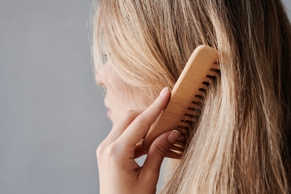 Close-up of blonde female hair combed with a wooden comb