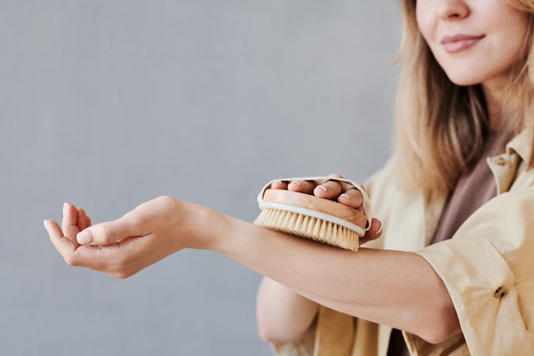 A woman in light clothes drying massages with an environmentally friendly brush on her forearm