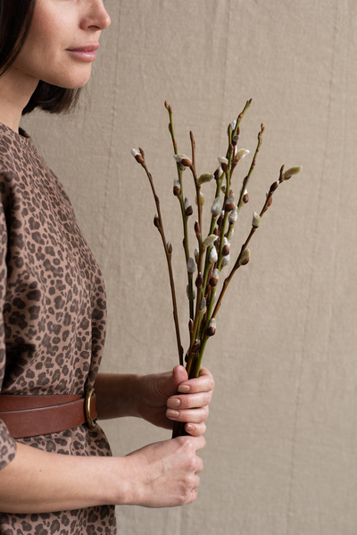 A bouquet of willow twigs for Easter in the hands of a woman in leopard print clothes