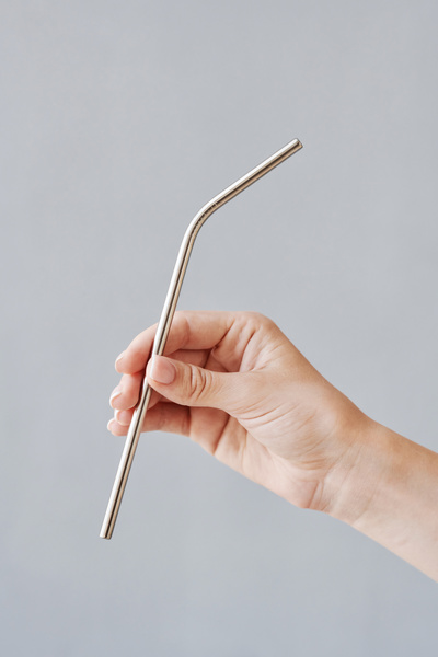 Iron straw for drinks in a womans hand against a light background