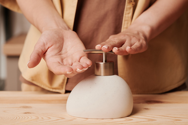A close-up of a beige soap dispenser liquid soap is going to be squeezed out from