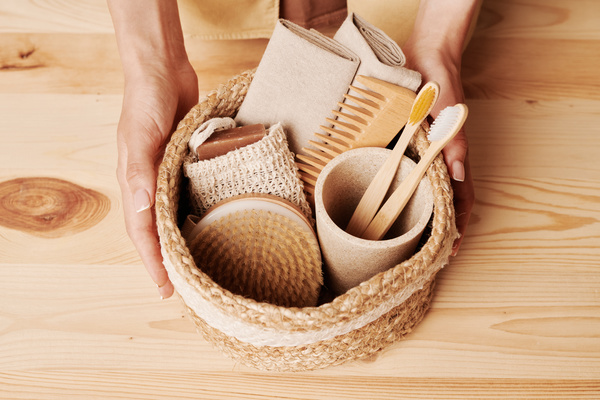 A woman touching wicker eco-friendly basket with toiletries on a wooden table is touched