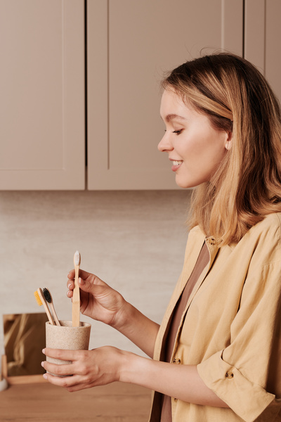 A woman with blonde hair dressed in a beige outfit with a light holder with environmentally friendly toothbrushes