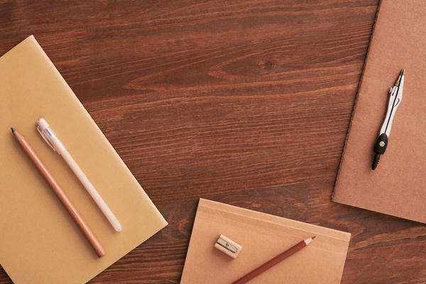 Brown notebooks and stylish office supplies laid out on a wooden table