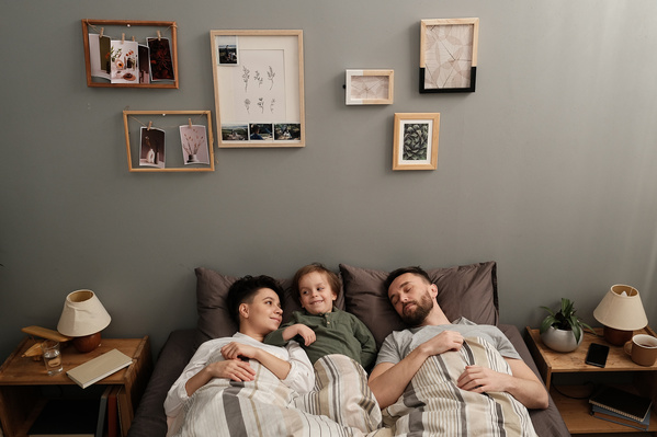 A smiling family consisting of young parents and their son lying in bed in the morning