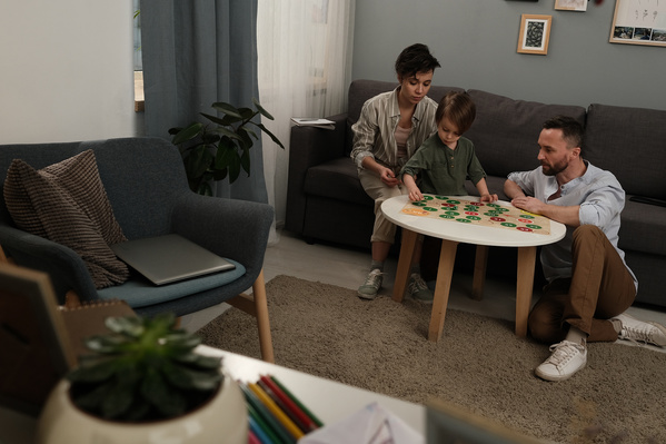 A boy in a green longsleeve playing a board game with his parents