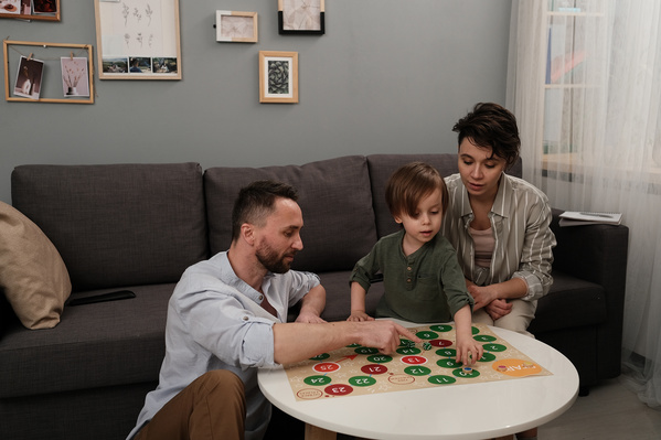 A child in a green longsleeve playing a board game with his parents
