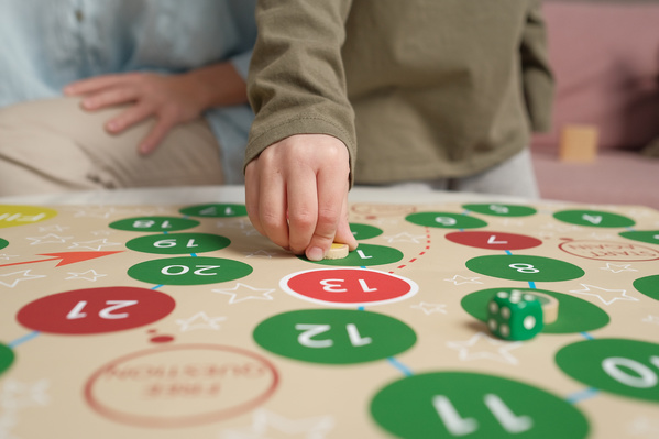 A boy in a brown longsleeve playing a board game with his mother