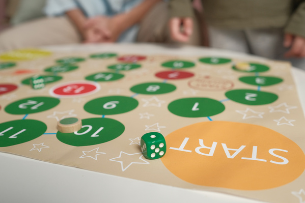 Close-up of a bright board game with a green dice on the table