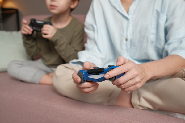 A woman in a light shirt playing a video game with her son with a blue joystick