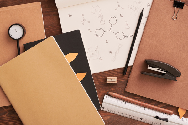 Chemistry notes in a notebook and stylish brown stationery laid out on a wooden table