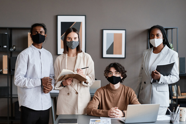Office employees in strict clothes and reusable face masks being in a modern office
