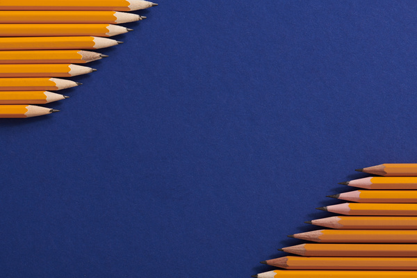 Top view of yellow graphite pencils beautifully laid out on a dark blue surface