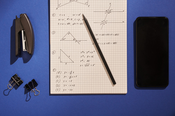 Study mathematical notes in a notebook with stationery and a black smartphone lying on a blue surface