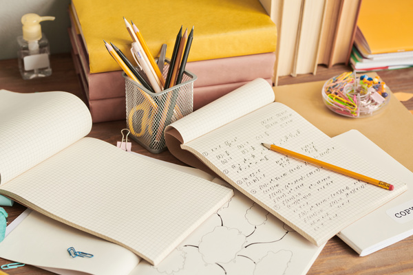 Study notebooks with jottings and a pencil lying on a wooden table with stationery