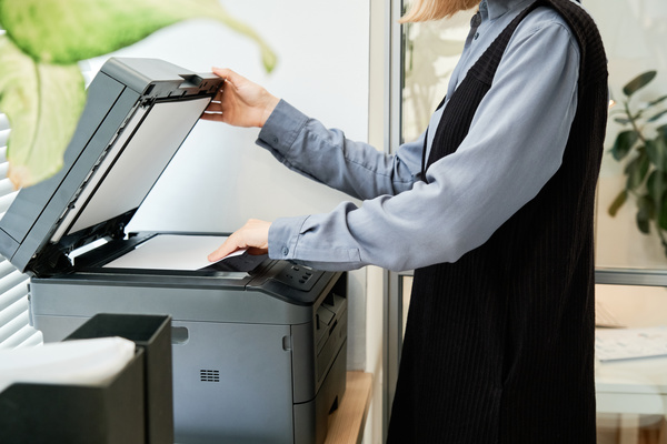 A woman with short blond hair dressed in strict clothes making photocopies of documents