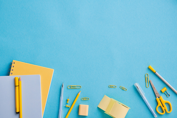 Yellow stationery set neatly laid out on a blue matte surface