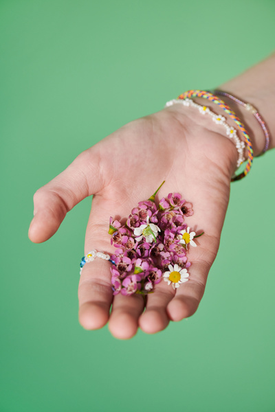 Close-up of multicolored flower buds in a womans hand with beaded bracelets on her wrist