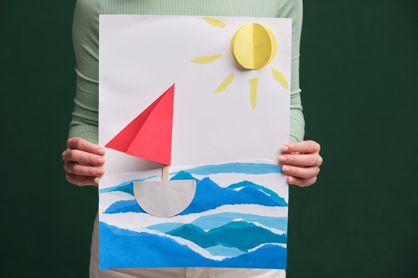 Paper applique in a summer marine theme in the hands of a woman in a green longsleeve