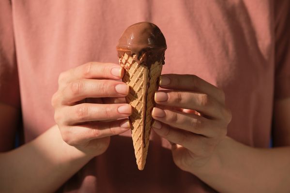 A woman in a red T-shirt holding a chocolate ice cream in a waffle cone