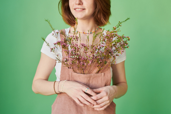 A woman with red hair in a pink corduroy sundress with pink wildflowers in her pocket