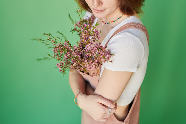 Pink wildflowers decorating a corduroy summer sundress of a red-haired woman