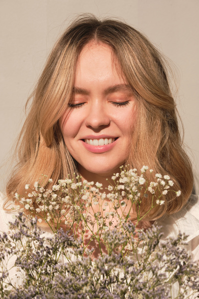 Portrait of a young blonde woman looking at small wildflowers of light shades