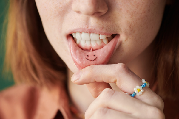 Close-up of a smiley tattoo on the inner lip of a woman with red hair