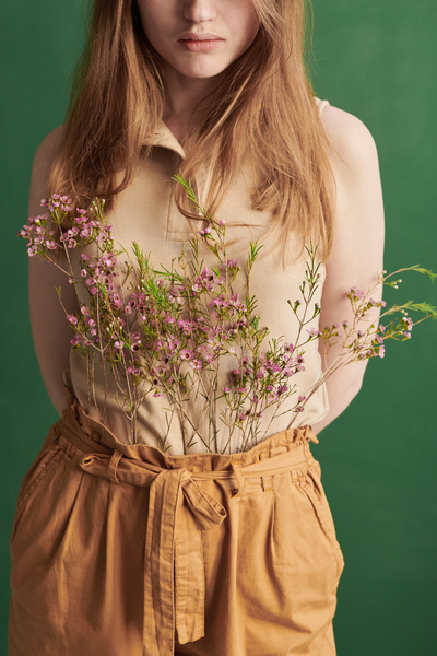 Pink wildflowers are placed in orange pants of a woman with long brown hair