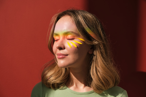 A blonde woman and yellow petals and rainbow rays on the face