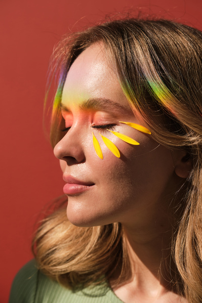 Yellow petals and rainbow rays on the womans face closing her eyes