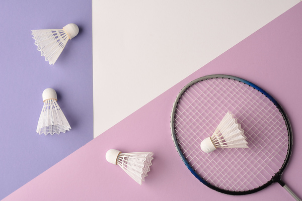 A racket and white badminton shuttlecocks beautifully laid out on the surface of pastel shades