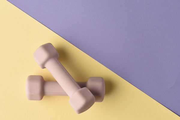 Pink fitness dumbbells lying on a yellow-purple surface