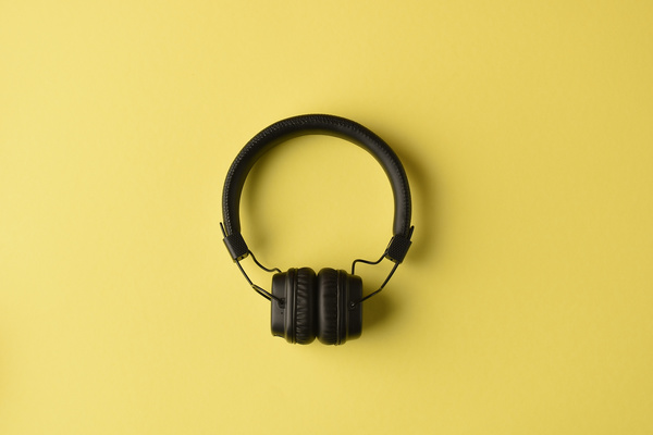 Top view of black headphones lying on a bright yellow surface