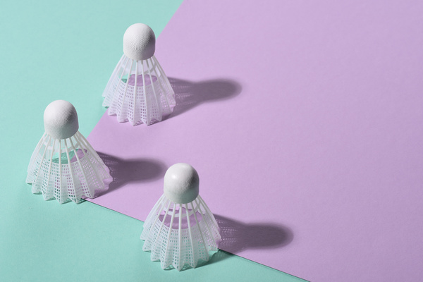 White badminton shuttlecocks standing on a two-color pink-turquoise surface